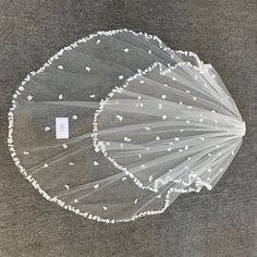 a veil with white flowers on it is laying on the floor in front of a gray background