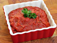 a red dish filled with sauce on top of a wooden table