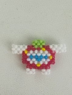 a beaded brooch sitting on top of a white table next to a wall