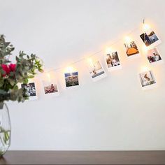 a vase filled with flowers sitting on top of a table next to a string of pictures