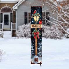 a welcome sign in front of a house with snow on the ground and trees around it