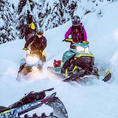 two people riding snowmobiles in the snow