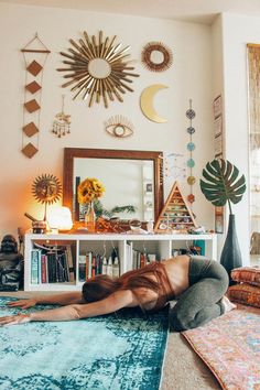 a woman laying on top of a blue rug in front of a mirror and bookshelf