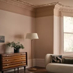 a living room with a couch, table and lamp in it's corner next to a window