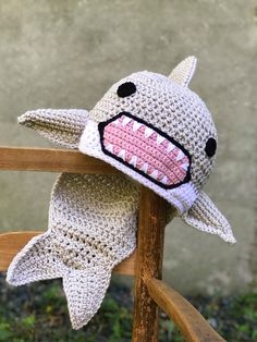 a crocheted shark hat on top of a wooden chair with its mouth open