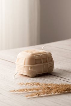 a plastic toy bus sitting on top of a wooden table next to some dry grass