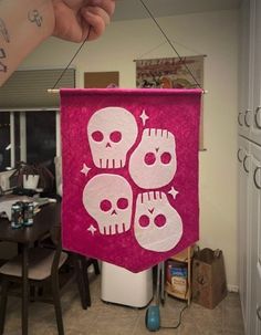 a pink banner with three skulls hanging from it's side in front of a dining room table