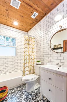 a white toilet sitting next to a bath tub under a bathroom mirror on top of a wooden ceiling