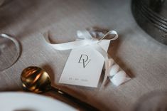 a table setting with white napkins and silverware, wine glass and place card