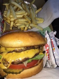 a cheeseburger with fries on the side and a bag of chips in the background