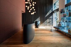 a room with wooden floors and large black vases hanging from the ceiling, along with bookshelves