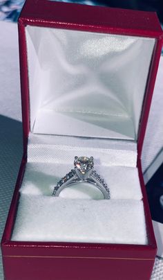 an engagement ring in a red box on a table