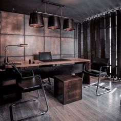 an office with wooden paneling and black leather chairs, two lamps hanging over the desk