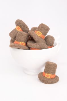 a white bowl filled with brown felt hats