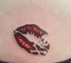 a woman's stomach with a skull and red lips tattoo on the side of her stomach