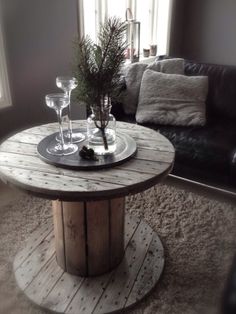 a wooden table with two wine glasses and a vase on it in front of a couch