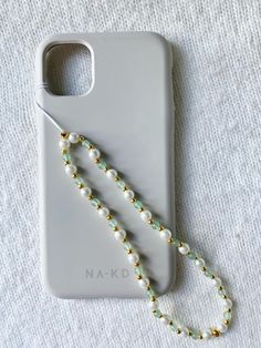 a white phone case with pearls and a lanyard