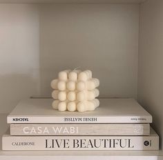 three books stacked on top of each other in front of a white wall and shelf