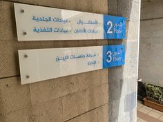 two blue and white signs are on the side of a building in arabic writing,