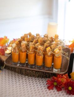 there are many small cups with food on the tray next to each other and candles