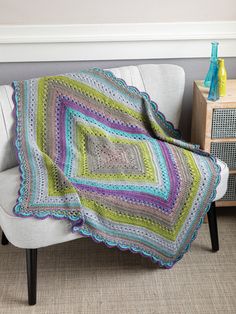 a crocheted blanket sitting on top of a white chair