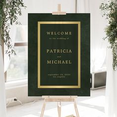 a green and gold wedding welcome sign in front of a window with potted plants