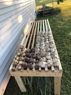 an outdoor vegetable garden with onions and other vegetables on a wooden bench in front of a house