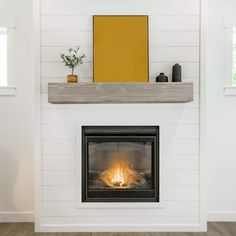 a white fireplace with a wood mantel and yellow painting on the wall above it