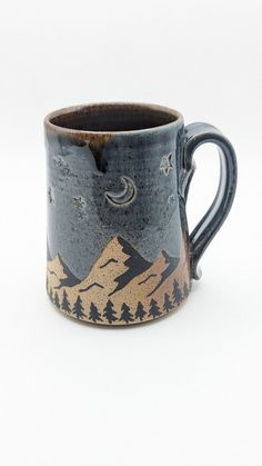 a ceramic mug with mountains and trees painted on the inside is sitting on a white surface