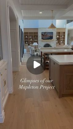 an open kitchen and living room with wood flooring in the center, and white cabinets on either side