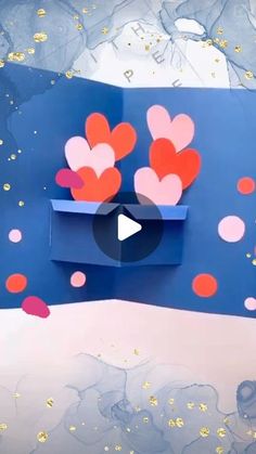 paper hearts in a blue box with gold confetti on the bottom and pink dots around it