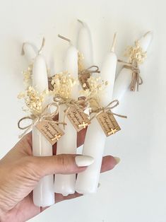 a hand holding several candles with tags attached to them