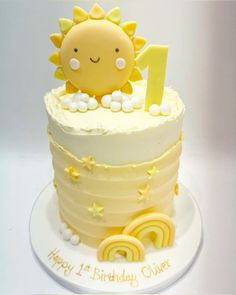 a white cake with yellow frosting and a sun decoration on top that says 1