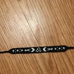 a black and white beaded bracelet sitting on top of a wooden table