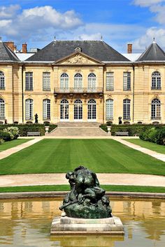 a large building with a fountain in front of it and lots of grass on the ground