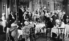 an old black and white photo of people sitting at tables in a fancy dining room