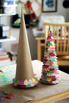 two paper christmas trees sitting on top of a table