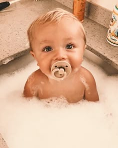 a baby in the bathtub with a pacifier