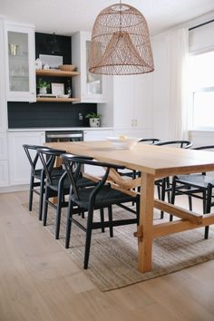 a dining room table with black chairs and a light fixture hanging from it's ceiling