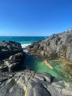 a person swimming in the ocean near some rocks