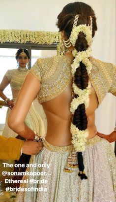 the back of a woman's dress with flowers in her hair and an elaborate braid