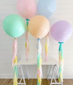 several balloons with tassels and ribbons hanging from them on a white chair in front of a wall