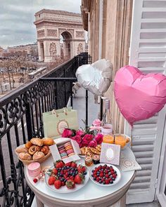 a table topped with lots of food and desserts next to a balcony overlooking the city