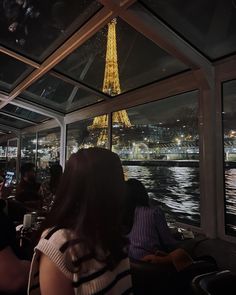 people are sitting at a table in front of the eiffel tower, looking out over the water