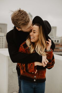 a man and woman embracing each other on top of a building