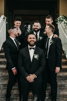 a group of men standing next to each other in front of a building with stairs