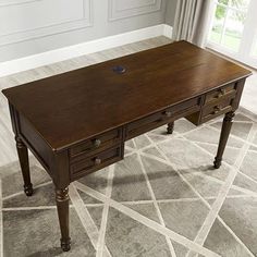 a wooden desk sitting on top of a carpeted floor in front of a window