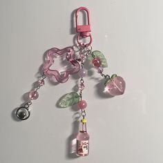 a pink keychain with charms attached to it's sides on a white surface