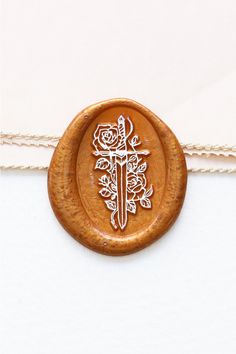 a wooden stamp with a knife and roses on it is attached to a white string