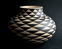 a black and white vase sitting on top of a dark table next to a wall